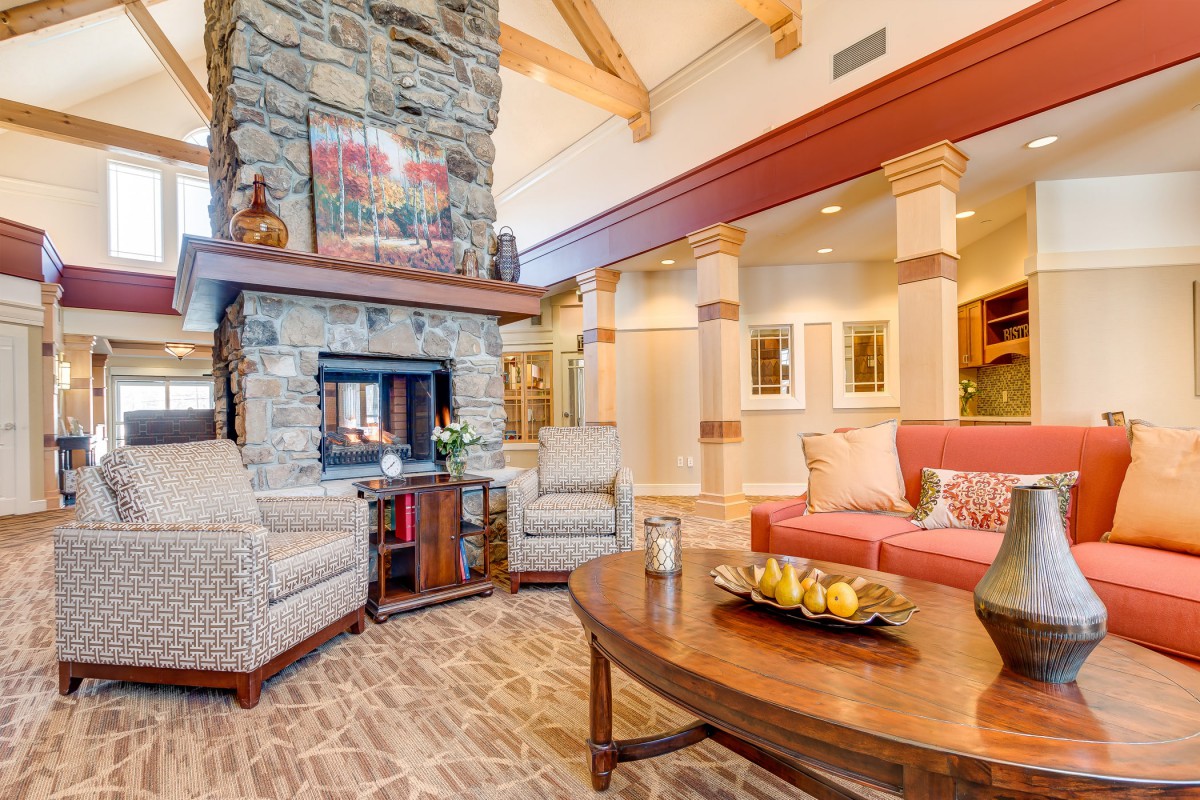 A cozy living room featuring a stone fireplace, comfortable seating, and wooden beams.
