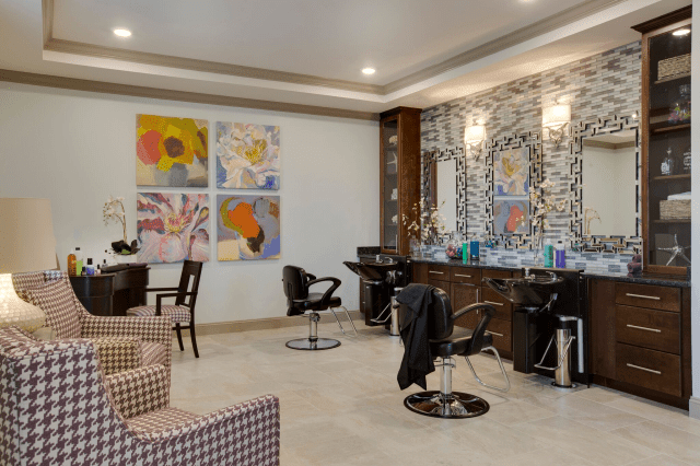 A modern salon interior featuring stylish chairs, mirrors, and vibrant artwork on the walls.