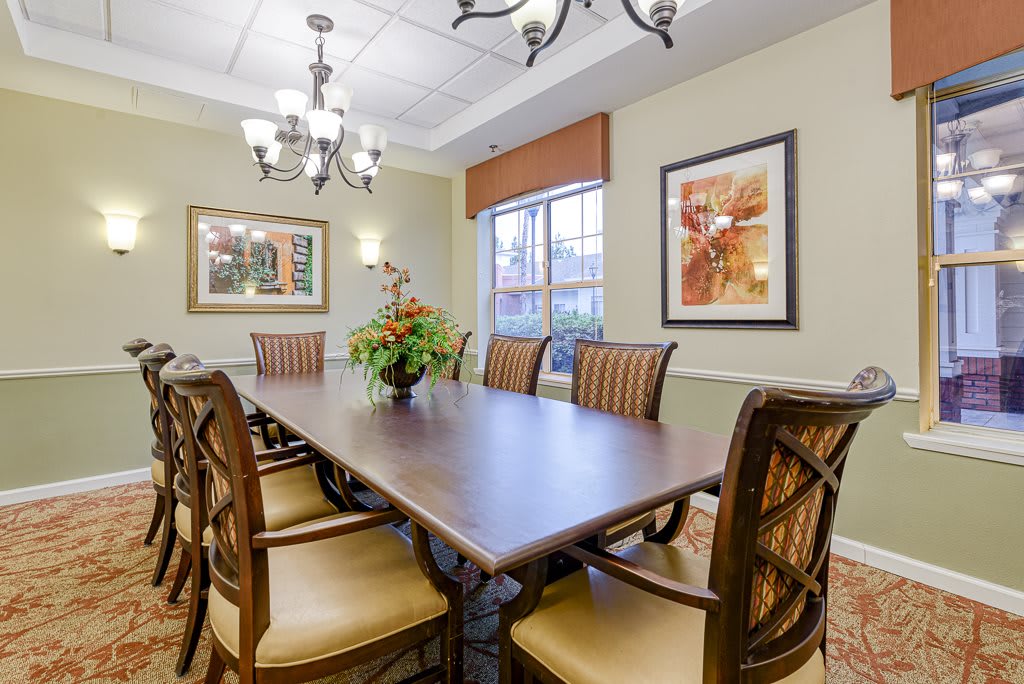 A well-decorated dining room featuring a large table with chairs, a chandelier, and artwork on the walls.