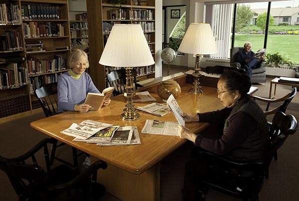 Two people reading at a table in a library.