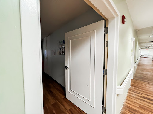 A view of an open door leading into a hallway with wooden flooring.