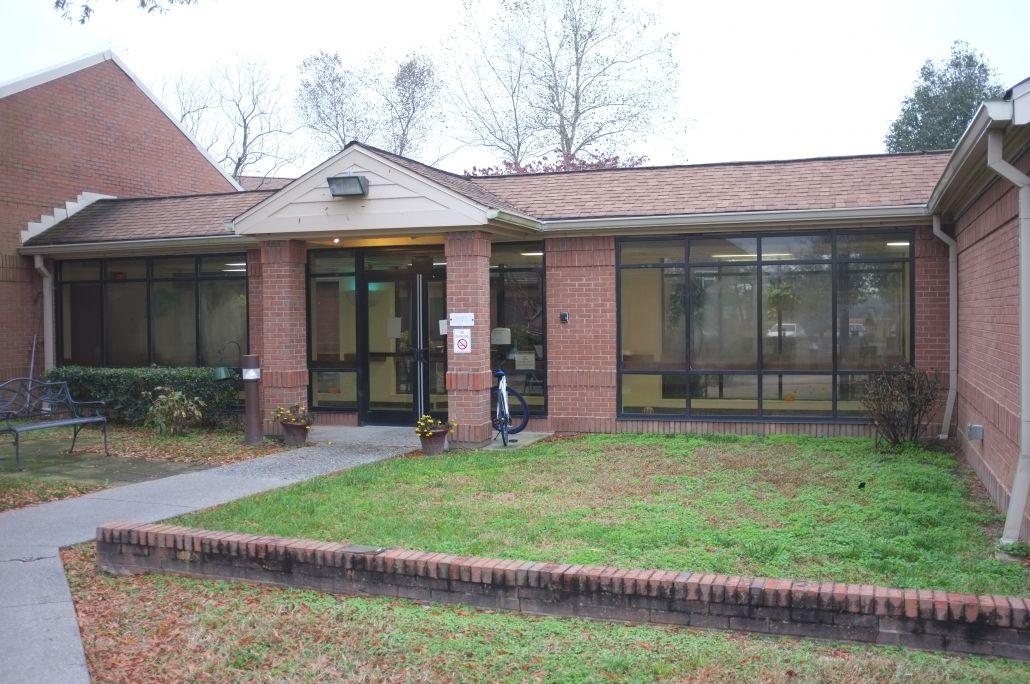 A small brick building with a glass entrance and surrounding windows.