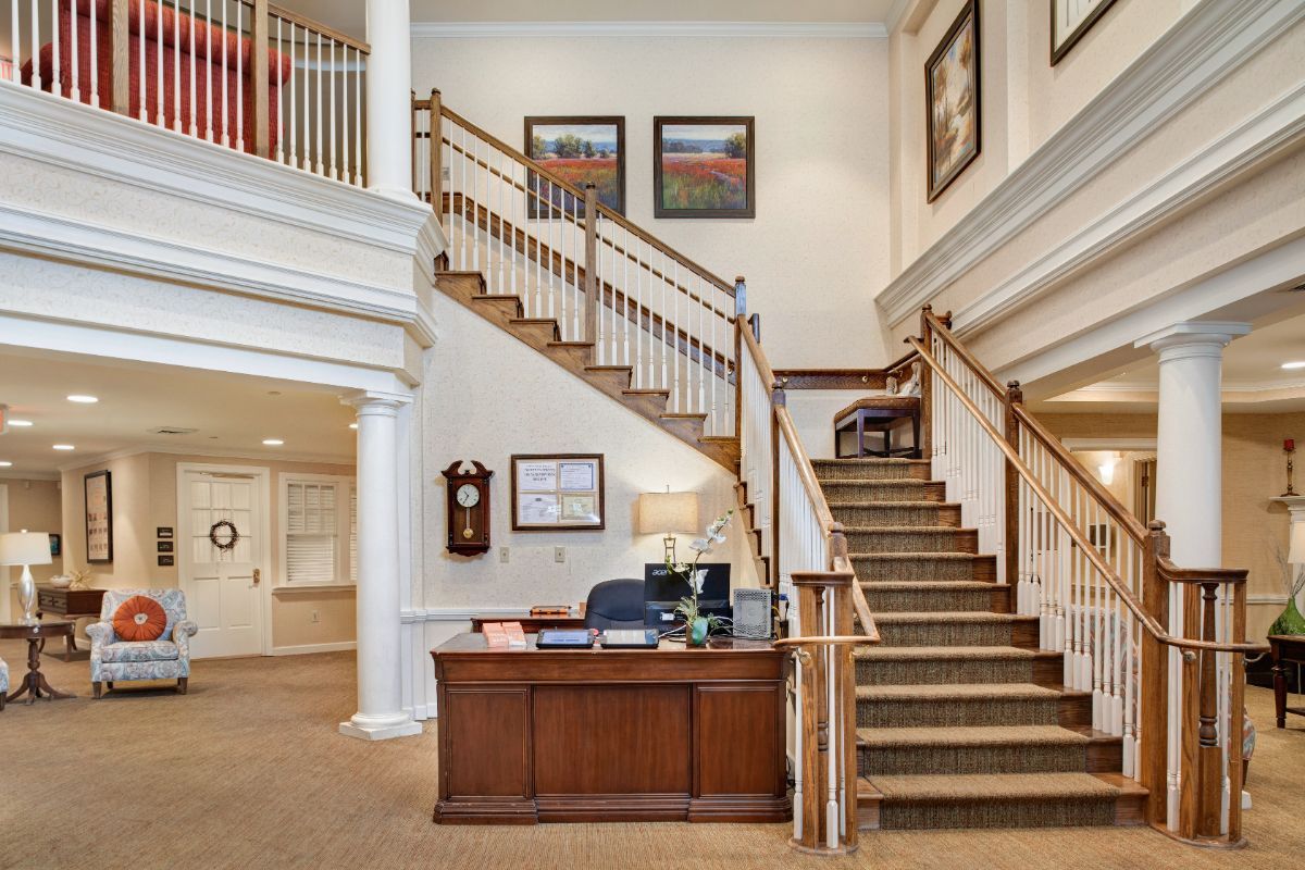 A welcoming lobby area featuring a wooden reception desk and a grand staircase with decorative railings.