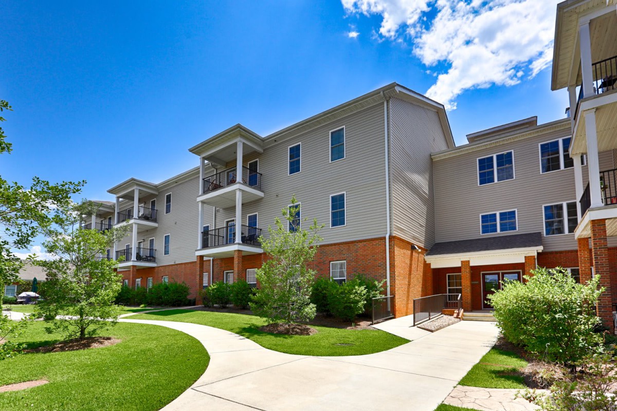 A modern apartment building with well-maintained landscaping on a sunny day.