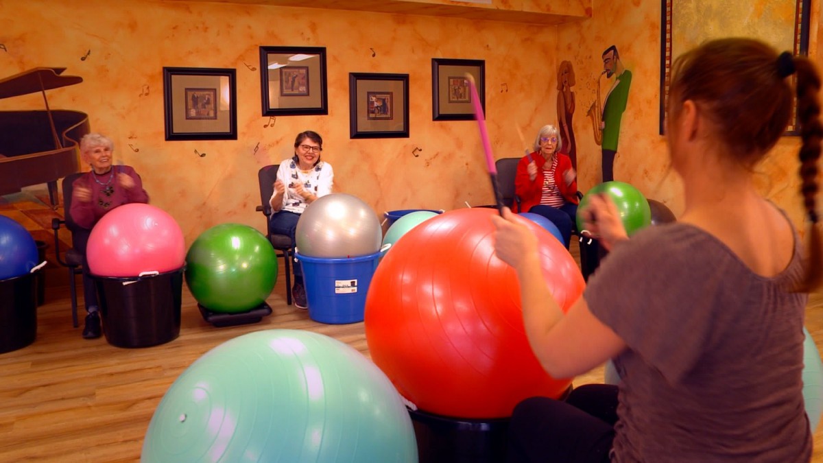 A group of people participating in a fitness class using large yoga balls indoors.
