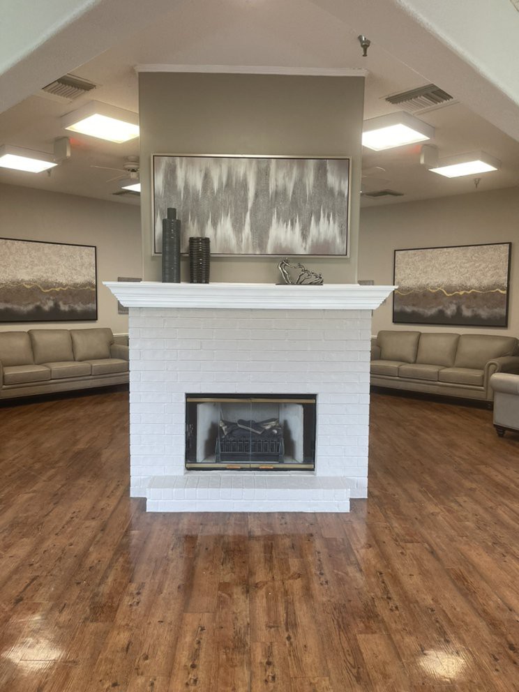 A modern lobby featuring a central fireplace, surrounded by sofas and contemporary artwork.