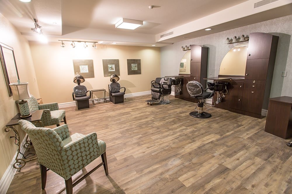 A cozy hair salon interior with wooden flooring, featuring chairs, mirrors, and hairdryers.