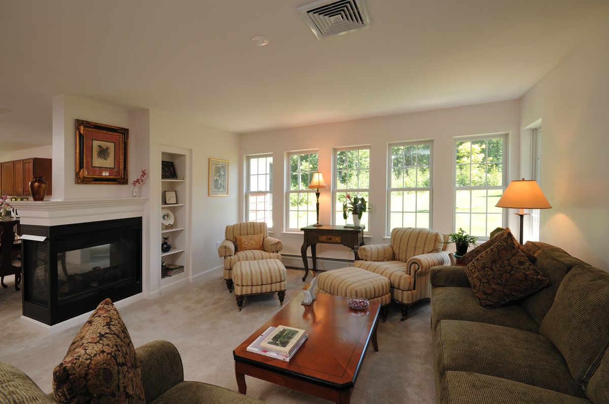 A cozy living room with comfortable seating, large windows, and a fireplace.