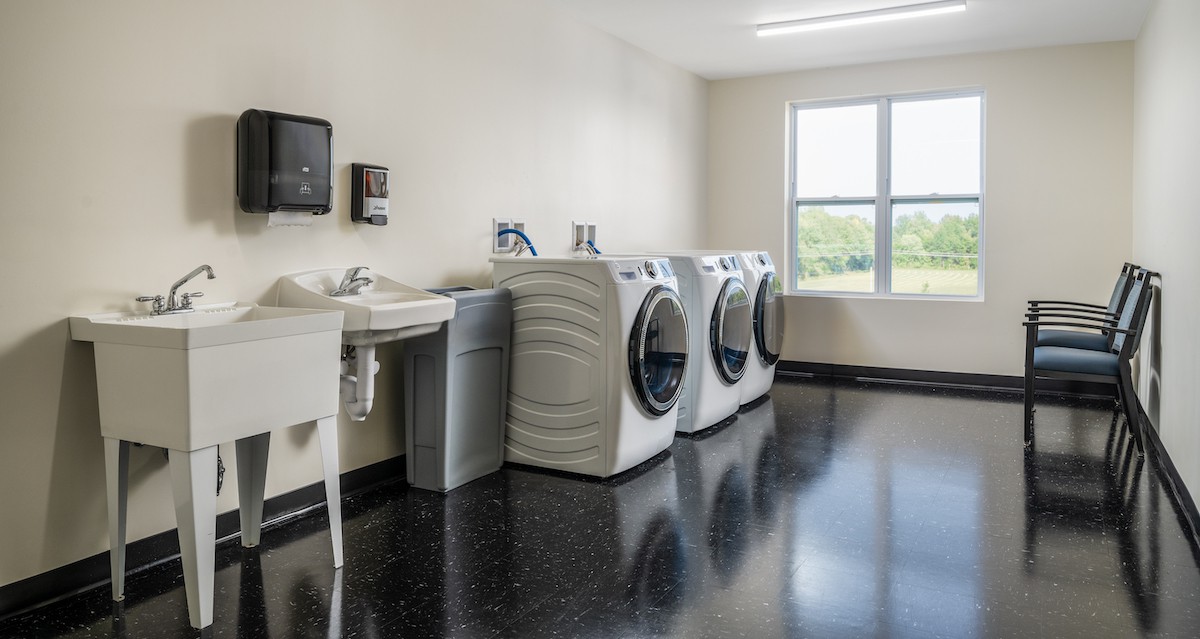 A clean and modern laundry room with washing machines and dryers lined up next to a sink.