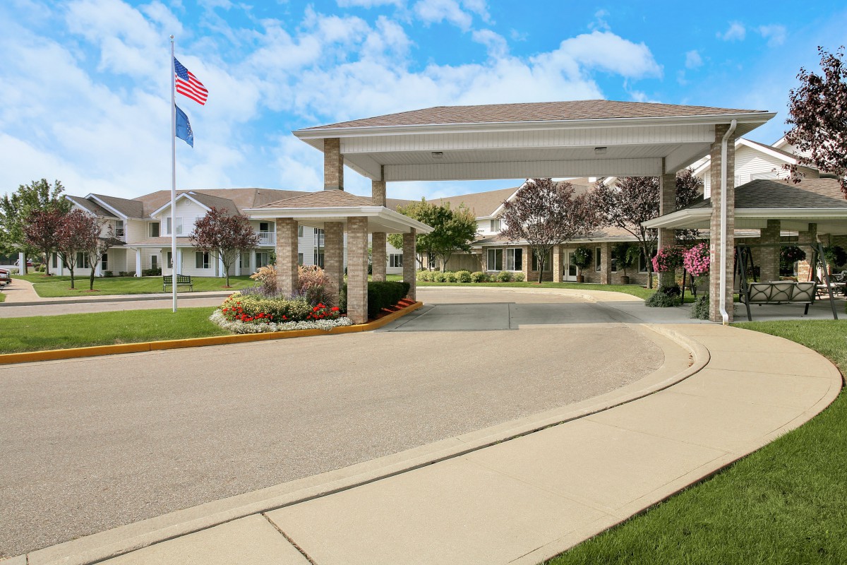A scenic view of a residential building entrance with a driveway and flag.