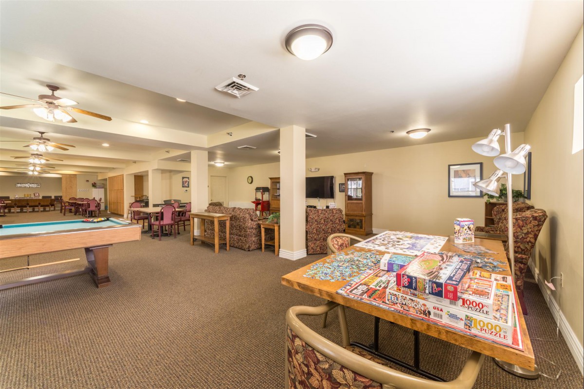 A spacious recreation room featuring tables set up with board games and puzzles, offering a comfortable environment for leisure activities.
