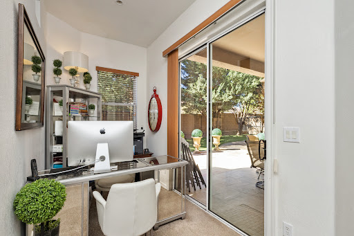 A bright and modern home office featuring a sleek desk, computer, and large glass doors leading to an outdoor space.