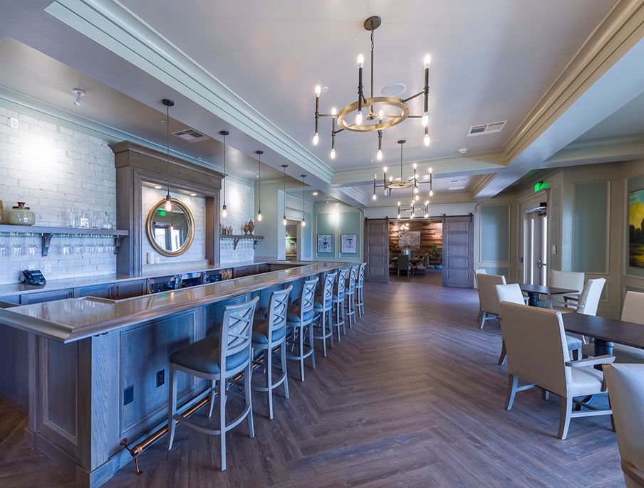 A modern, luxurious bar interior with elegant chandeliers and ample seating.