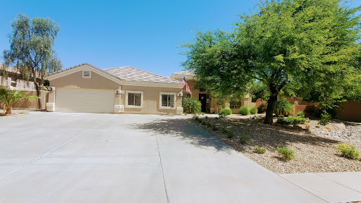 A charming single-story house with a spacious driveway and well-maintained front yard under a clear blue sky.
