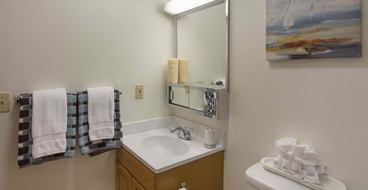 A small bathroom with a sink, mirror, and neatly arranged towels.