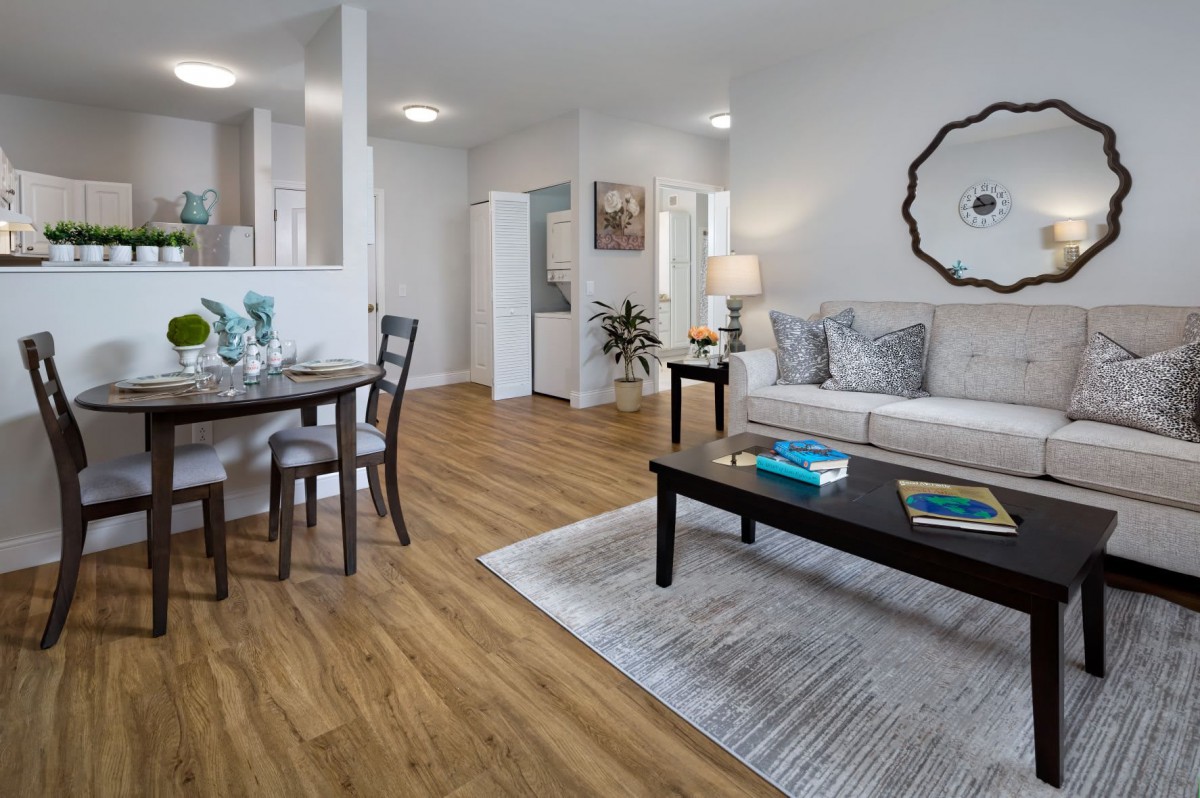A modern living room with wood flooring, featuring a sofa, coffee table, and dining area.