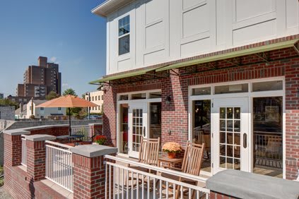 A cozy outdoor patio with wooden furniture and an umbrella on a sunny day.