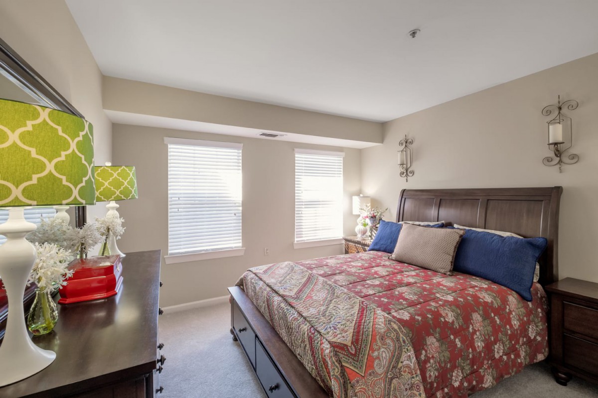 A cozy bedroom with a large bed, two windows, and stylish decor.