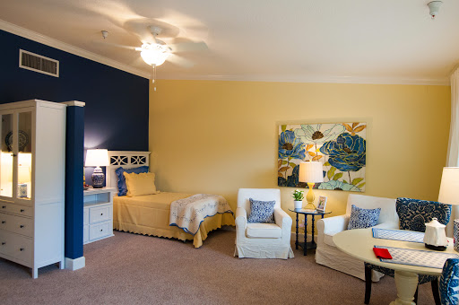 A brightly colored bedroom featuring a single bed, comfortable seating, and decorative artwork.