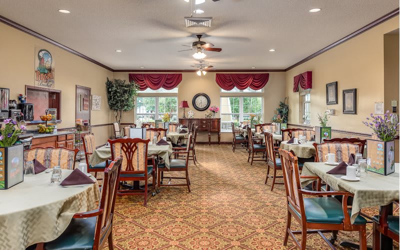 A well-decorated dining area with neatly arranged tables and chairs, featuring classic interior design elements.