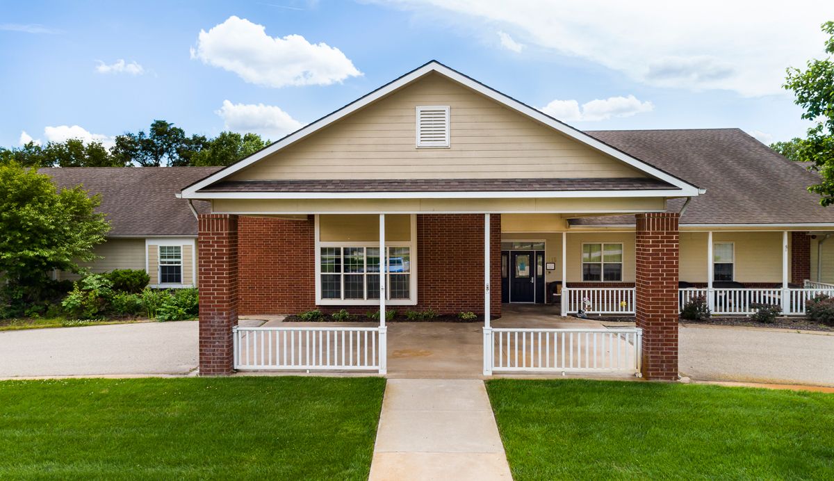 A single-story brick house with a covered porch and well-maintained lawn.