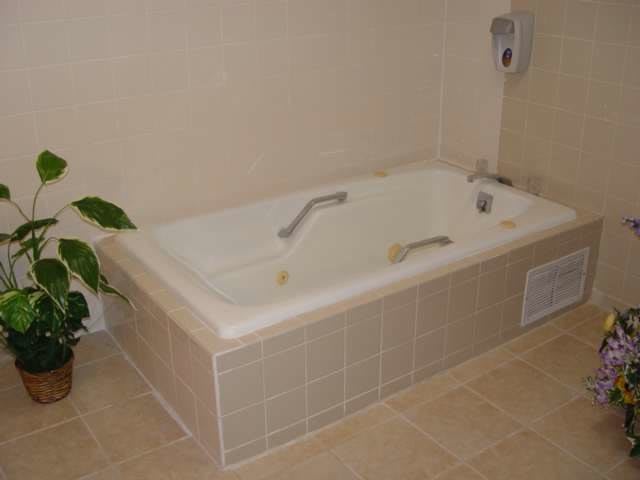 A tiled bathtub in a bathroom setting, equipped with grab bars.