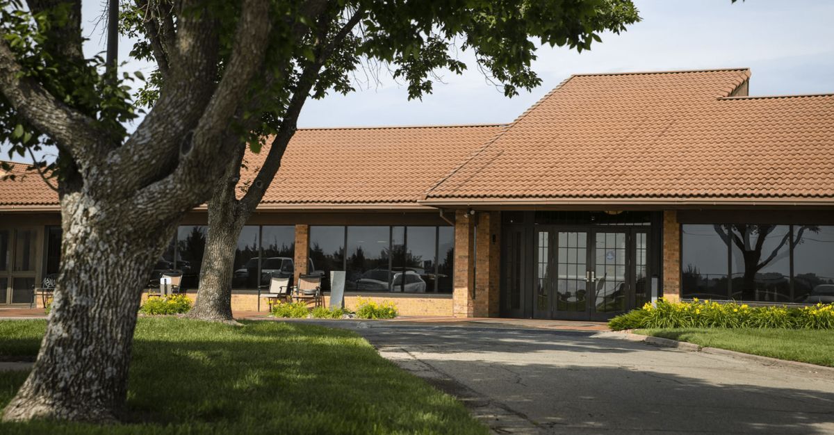 A building with a brown roof and large windows surrounded by trees.