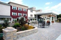 A modern building with an outdoor patio area featuring chairs and tables.