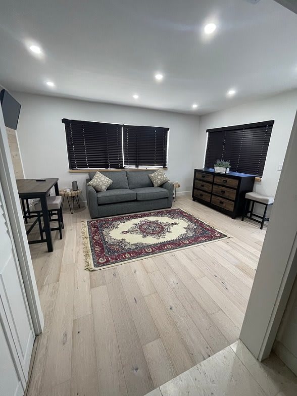 A modern living room with a sofa, decorative rug, and dining area.
