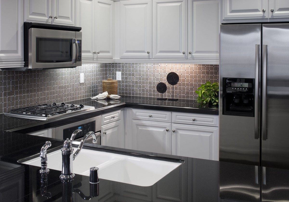 A modern kitchen with white cabinets, stainless steel appliances, and a sleek black countertop.
