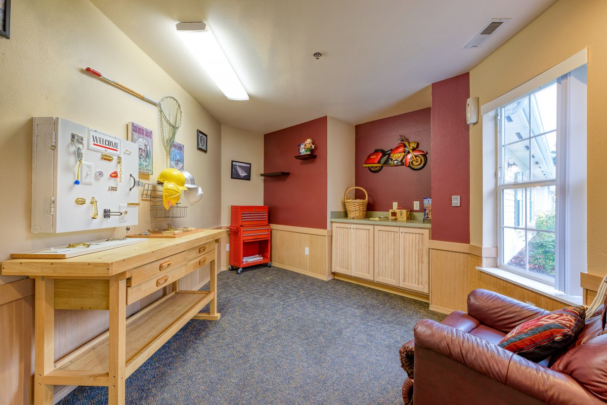 A cozy craft room with a work table, chair, and colorful decorations.