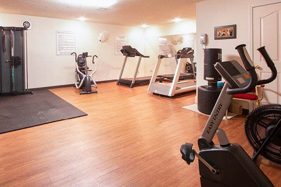 A well-equipped gym with treadmills and exercise machines on a wooden floor.