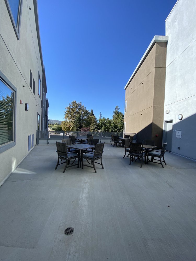 An outdoor patio area with tables and chairs between two buildings on a clear day.