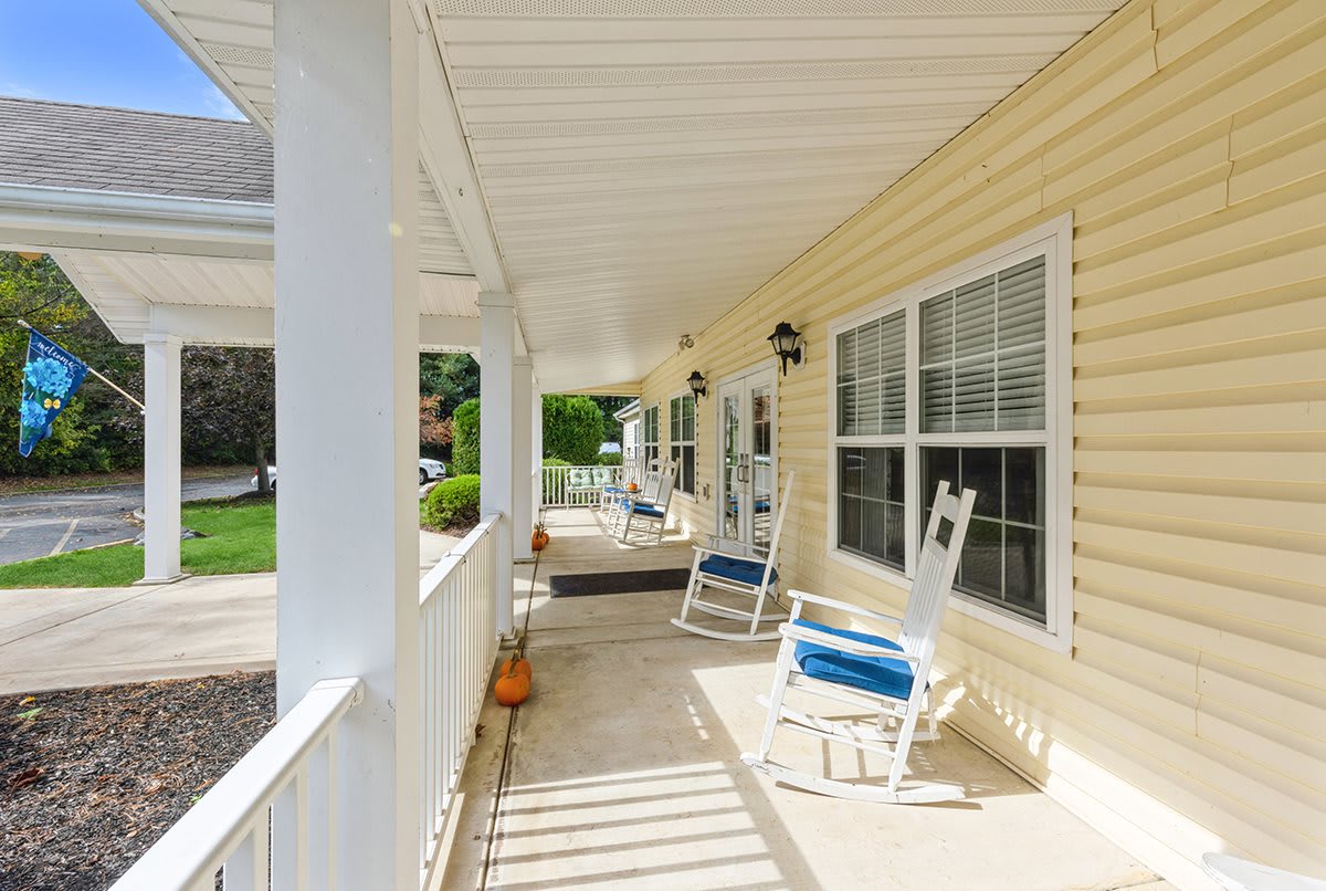 A peaceful porch with rocking chairs and a white railing, perfect for relaxing.