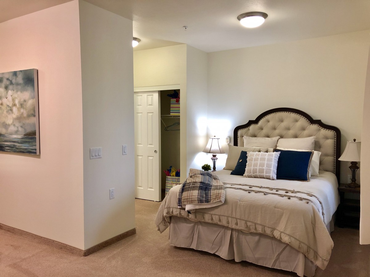 A cozy bedroom with elegant decor, featuring a neatly made bed adorned with cushions and bedside lamps.