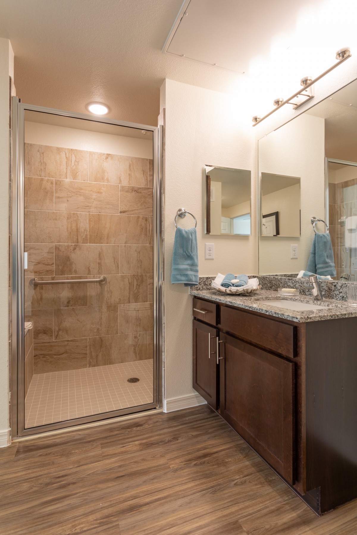 A modern bathroom with a glass-enclosed shower and a vanity featuring a marble countertop.