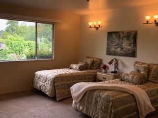 A cozy bedroom with twin beds, warm lighting, and a scenic view through the window.