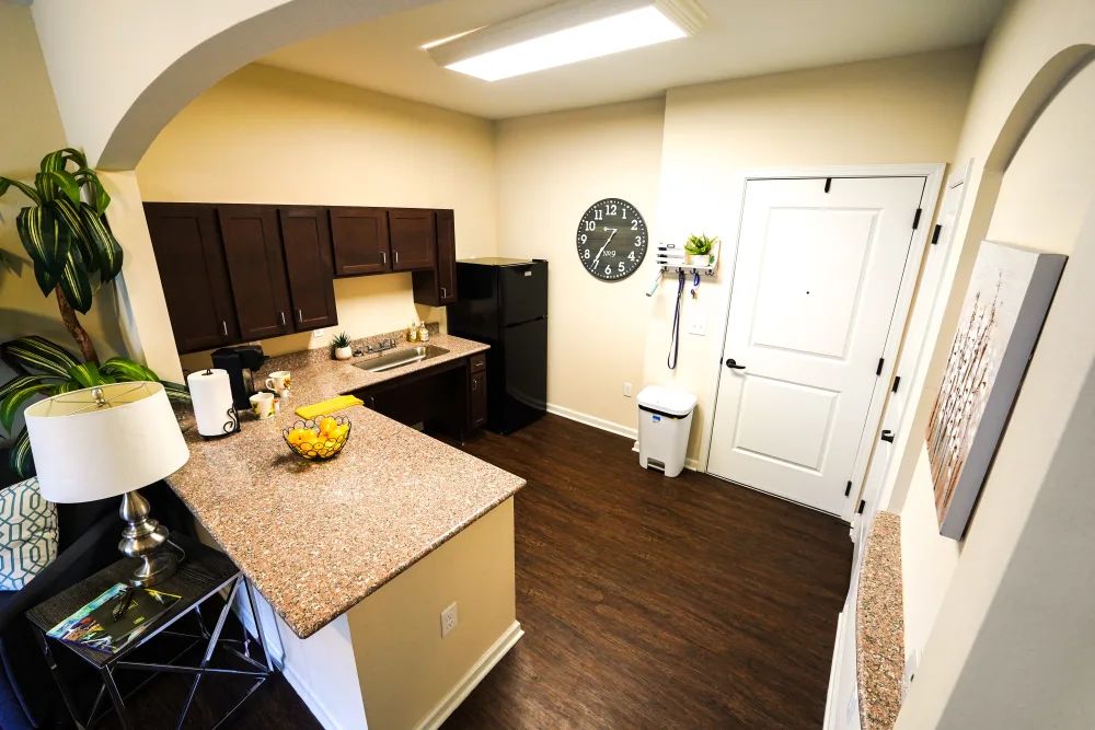 A modern kitchen with dark cabinets, a spacious countertop, and a wall clock.
