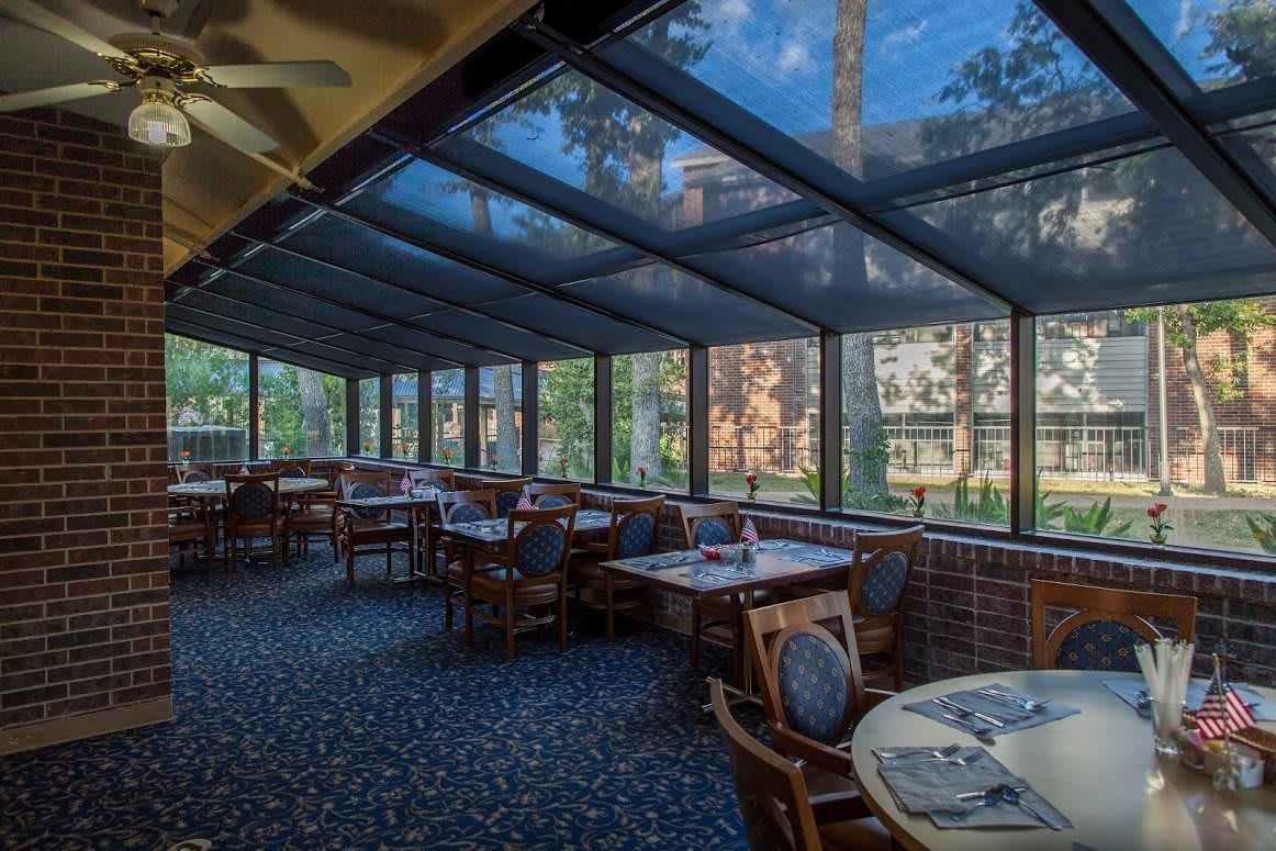 A beautifully lit restaurant with a glass ceiling and large windows offering views of the outdoors.