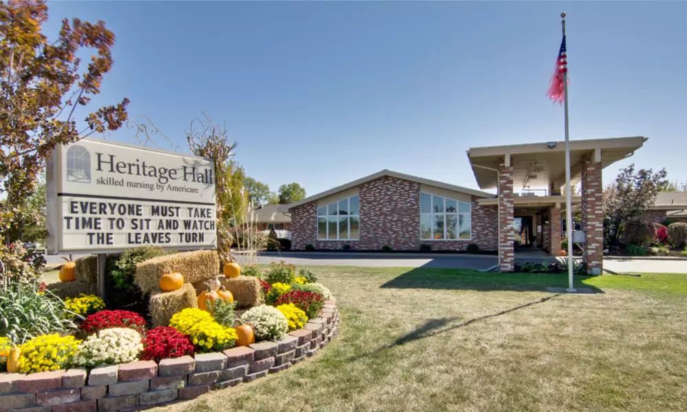 A building with a stone facade, surrounded by a landscaped area featuring autumn flowers and a sign that reads 'Vintage Hills'.