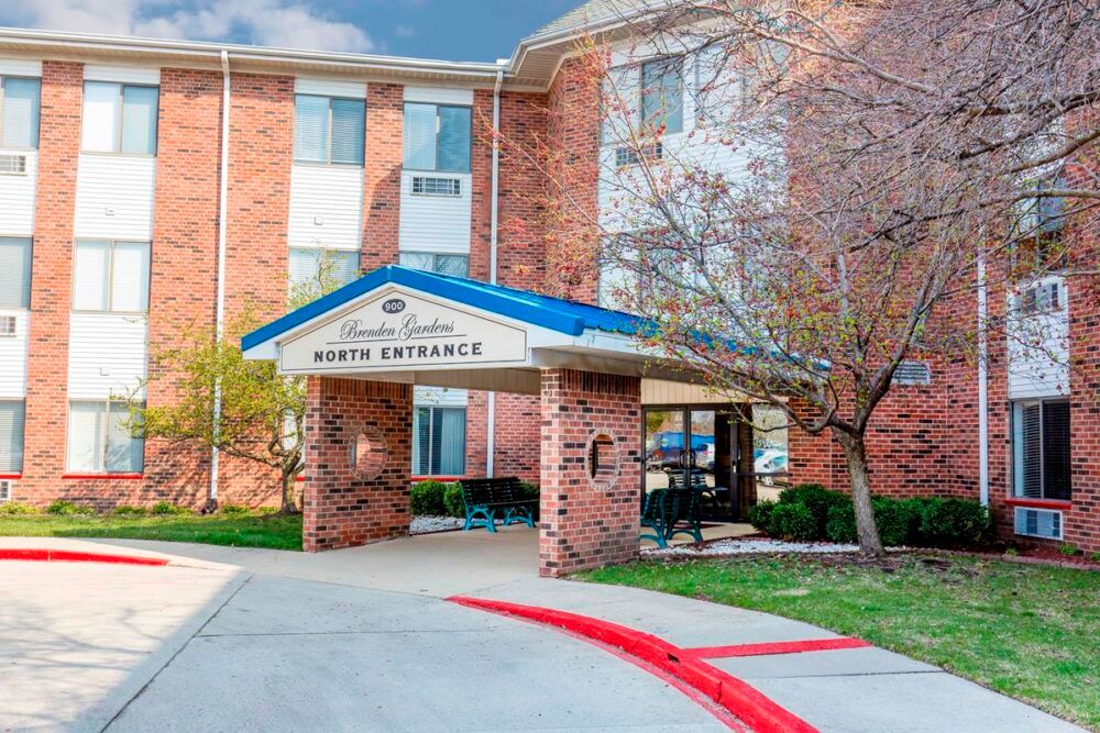 Entrance of a brick hotel building with landscaped surroundings.
