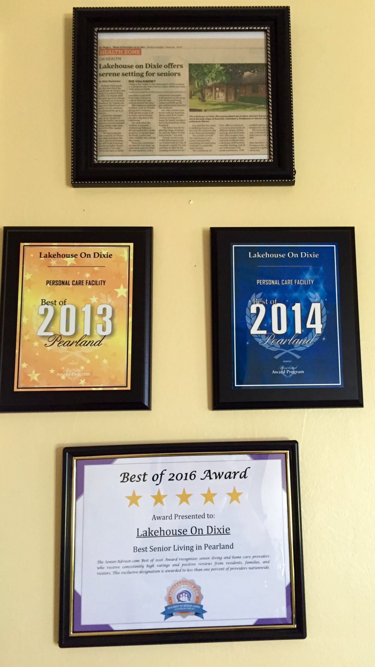 A collection of framed award plaques on a wall, showcasing achievements from the years 2013 and 2014.