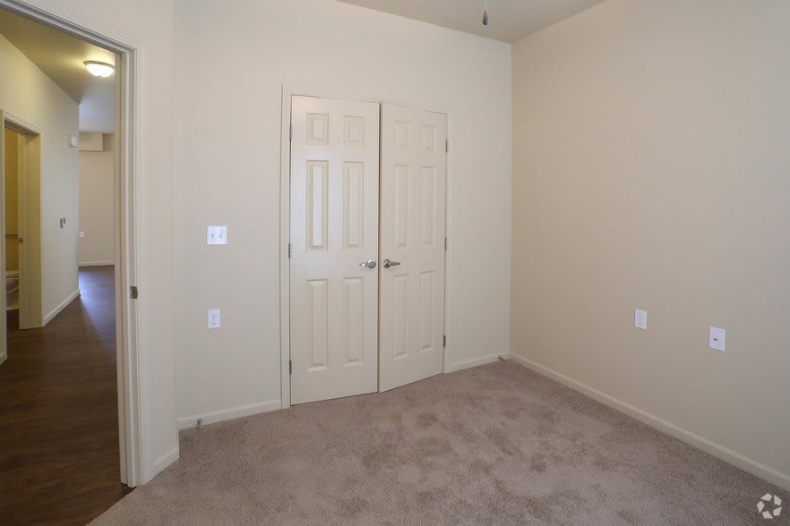 A simple empty room with carpet flooring and double doors.