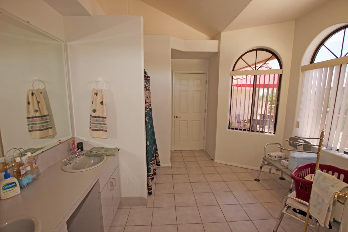 A bright bathroom with a tile floor and arched window.