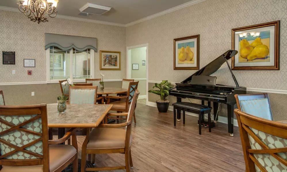 A cozy dining area featuring a piano, artwork, and wooden furniture.