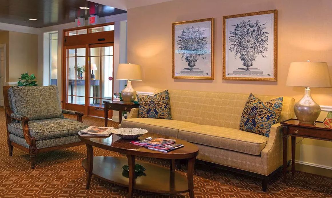 A cozy living room with a sofa, coffee table, lamp, and decorative artwork on the wall.