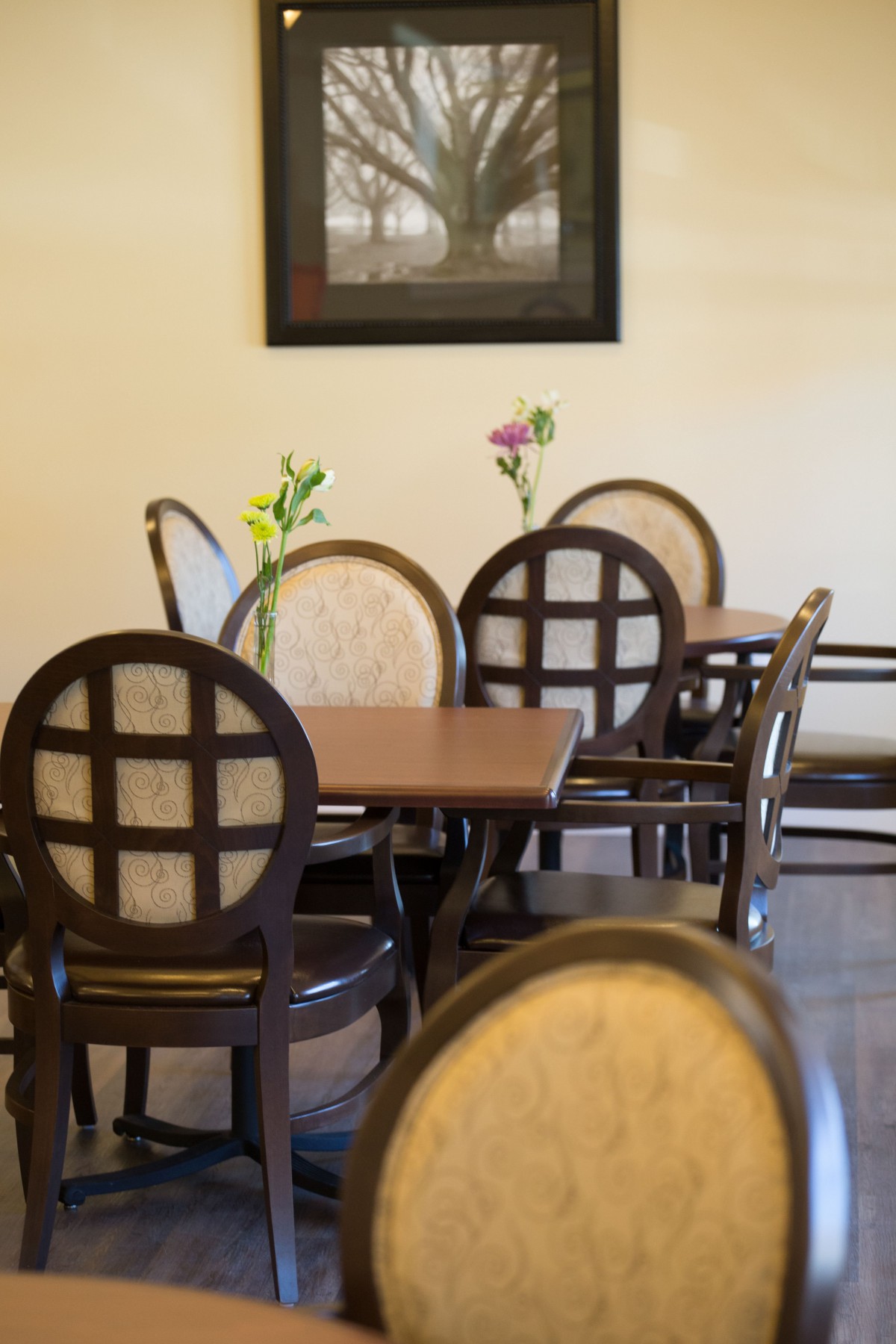 A cozy dining area with neatly arranged tables and chairs, each adorned with a small vase of flowers.