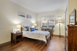 A cozy and well-decorated bedroom with wooden flooring, featuring a bed, bedside tables, and lamps.