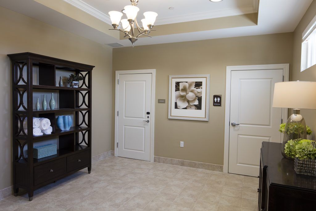 A neatly arranged office waiting room with a bookshelf and artwork on the wall.