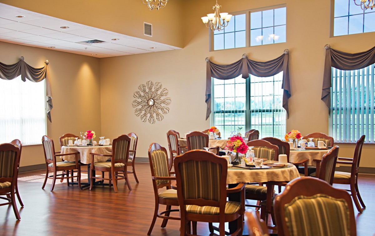 An elegant dining room with neatly arranged tables and chairs, complemented by decorative elements and large windows.